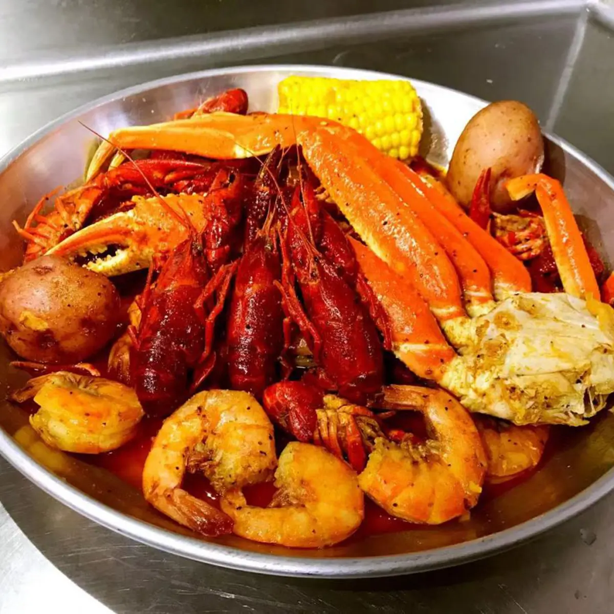Metal bowl loaded seafood boil snow crab crawfish shrimp corn potato at Red Crab Juicy Seafood, a Seafood Restaurant in Brooklyn
