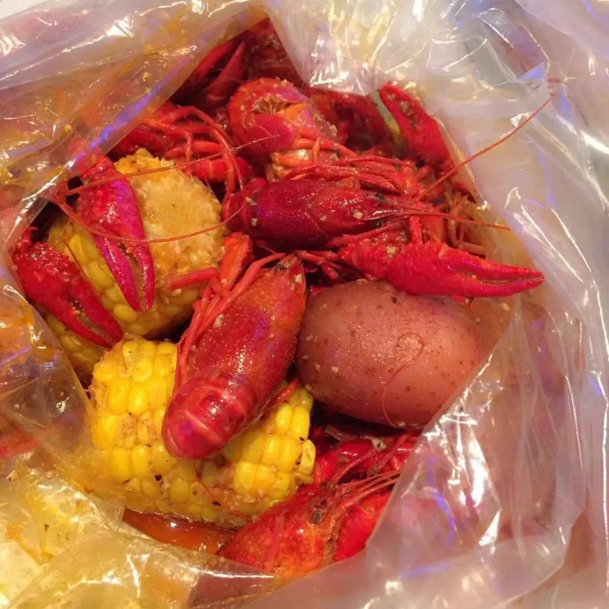 Spicy crawfish corn potato seafood boil packed in plastic bag at Red Crab Juicy Seafood, a Seafood Restaurant in Brooklyn